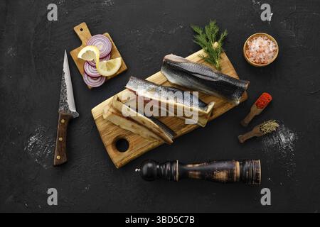 Roher, frisch gefrorener Heringskadaver mit Gewürzen auf Schneidebrett Stockfoto