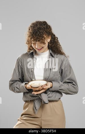 Die lächelnde Frau hält einen Teller voller Pillen in den Händen Stockfoto
