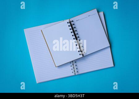Zwei offene Notizbücher auf blauer Oberfläche. Flache Lagen oder Draufsicht. Stockfoto