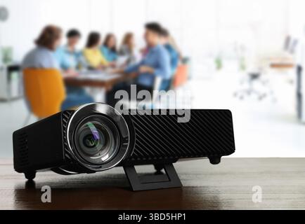 Moderner Videoprojektor auf Holztisch und Personen, die im Konferenzraum arbeiten, selektiver Fokus Stockfoto