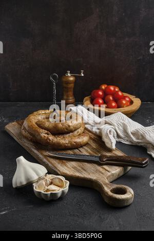 Pferdefleischwurst mit Knoblauch auf Holzschneidebrett gerollt Stockfoto