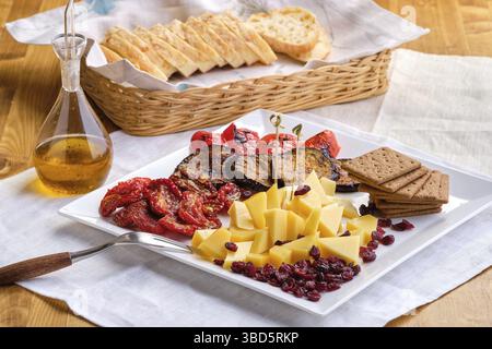 Set mit verschiedenen Vorspeisen für Wein, Käse, sonnengetrocknete Tomaten, geröstete Auberginen, Paprika, Hardtack und getrocknete Preiselbeere Stockfoto