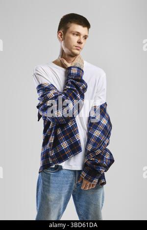 Junger, übermütiger Mann in kariertem Hemd und Jeans, die seinen Hals berühren Stockfoto