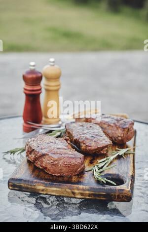 Gegrillte New York Strip Steaks auf dem Glastisch im Hinterhof Stockfoto