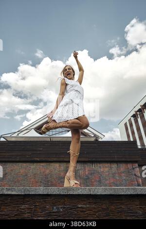 Eine junge, fröhliche Frau tanzt an einem sonnigen Tag in einem Stadtpark Stockfoto