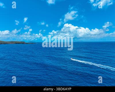 Luftaufnahme eines Motorbootes, das tiefblaue Gewässer überquert und die Inselküste im Blick hat Stockfoto