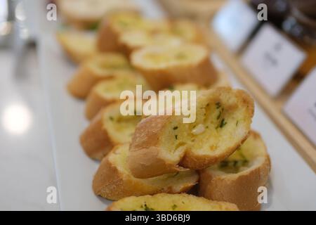 Drei Scheiben Knoblauchbrot mit frischer Petersilie auf einer weißen Keramikplatte isoliert auf weiß. Draufsicht. Hochwertige Fotos Stockfoto