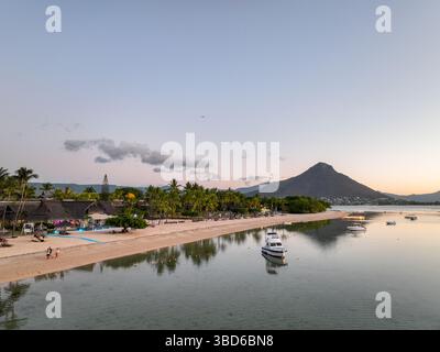 Kleine Boote schweben auf ruhigen Gewässern in der Nähe von Le Morne, Mauritius mit Bergen und Strand im Dämmerlicht Stockfoto