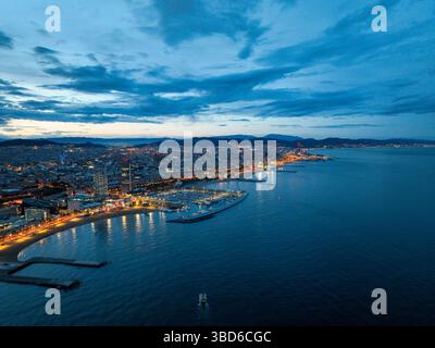 Blick aus der Vogelperspektive auf den beleuchteten Strand von Barcelona und die Skyline der Stadt zur blauen Stunde Stockfoto