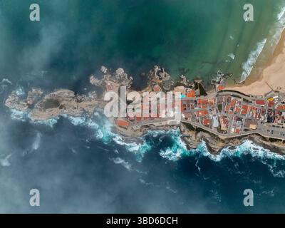 Direktes Bild der Drohne über dem Baleal Dorf und Klippen treffen auf raues Meer Stockfoto