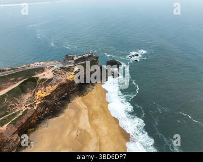 Blick von oben auf die historische Küstenfestung auf felsigen Klippen über Strand und Wellen Stockfoto