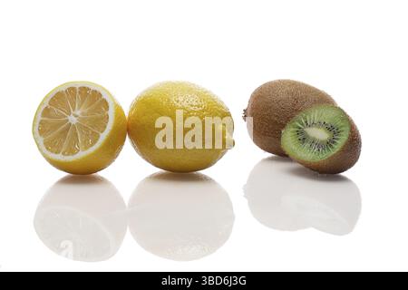 Eine ganze und eine Hälfte Zitrone und Kiwi mit Reflexion auf einem weißen Glastisch Stockfoto