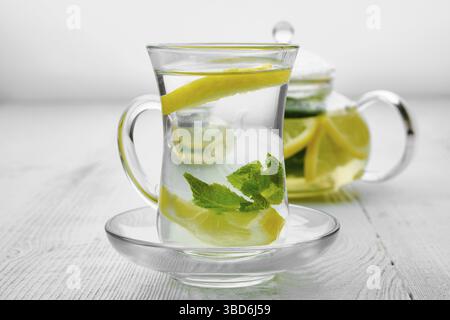 Antioxidative Heißgetränk mit Zitrone und Minze in transparentem Tee Topf und Glas Stockfoto