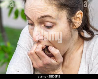 Eine Nahaufnahme einer Hirschzecke, die am Arm einer Person herumkriecht. Die Arachnide ist rötlich gefärbt und hat ihre Beine als Kriechen ausgestreckt Stockfoto