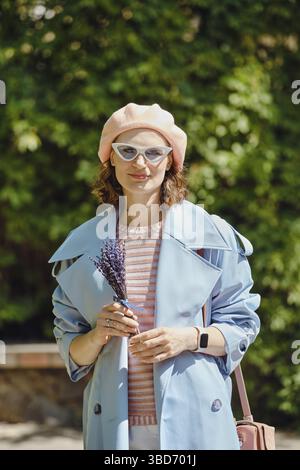 Außenporträt einer fröhlichen, modischen Frau mit Lavendel in den Händen Stockfoto