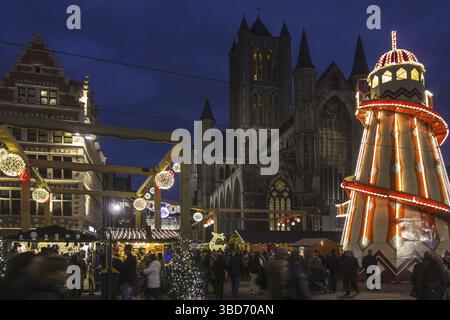 Beleuchtete Helterskelette und Leute, die im Winter auf dem Weihnachtsmarkt am Abend einkaufen, Korenmarkt, Maismarkt, Gent, Belgien Stockfoto