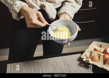 Nahaufnahme der Hände einer Frau, die Eier in einer Omeletteschüssel schlagt Stockfoto