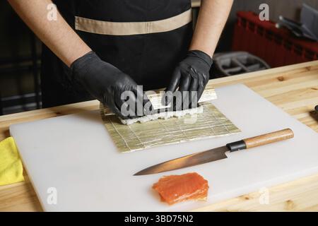 Hände des Küchenchefs, der Lachsbrötchen zubereitet Stockfoto