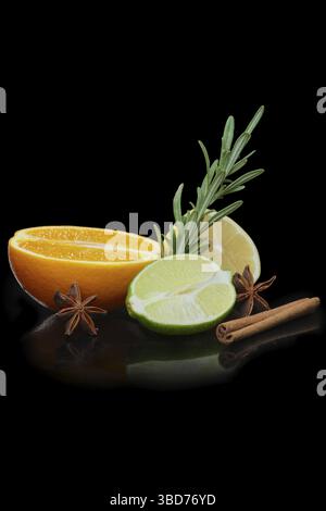 Eine Hälfte Orange, Zitrone und Limette, dekoriert mit Zimt, Sternanis und Rosmarin. Foto mit isoliertem Beschneidungspfad auf Schwarz Stockfoto