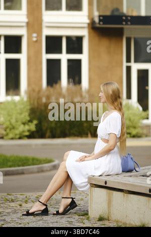 Seitenansicht einer jungen Frau, die im Profil auf einer Bank im Wohnbereich sitzt Stockfoto