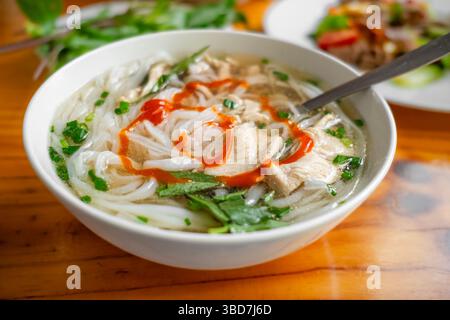 Pho-Suppe mit Nudeln und Hähnchenfleisch, frisches Gemüse, auf einem Teller, vietnamesische Küche, hausgemachte Speisen, auf einem Tisch. Asiatische Nudelsuppe. Niemand, Draufsicht, Stockfoto