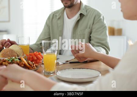 Familie betet zusammen vor dem Abendessen am Tisch drinnen, Nahaufnahme Stockfoto