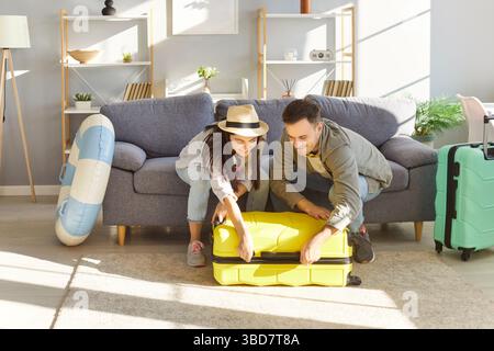 Ein Paar packt mit Begeisterung seinen Koffer in Vorbereitung auf den bevorstehenden Sommerurlaub. Stockfoto