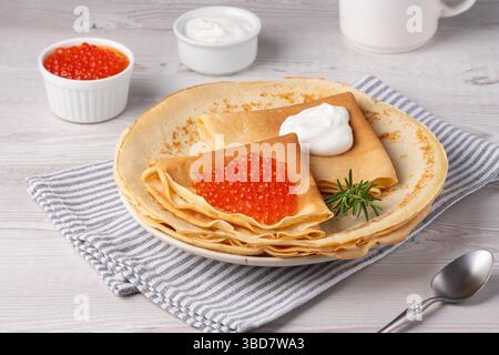 Köstliche Crepes mit rotem Kaviar serviert auf einem gemütlichen Tisch bei Tageslicht Stockfoto