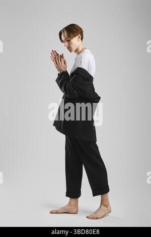 Junger Barfußmann in schwarzem Anzug posiert im Studio Stockfoto