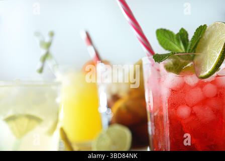 Detail mehrerer Gläser mit alkoholfreien Getränken verschiedener Geschmacksrichtungen mit Eis und Strohhalmen auf weißem Hintergrund. Vorderansicht. Stockfoto