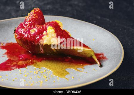Nahaufnahme von süß gebackenen Birnen mit Mascarpone, Karamellsirup und Erdbeermarmelade Stockfoto