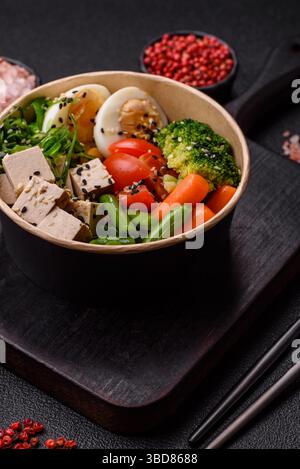 Veganer Salat, Schüsseln mit Kichererbsen, Brokkoli, Tomaten, Tofu-Käse und gekochten Eiern. Vegetarische Mahlzeit mit Gemüse, Samen und Körnern Stockfoto