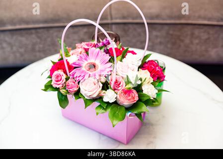 Wunderschöne Blumenarrangements mit Rosen, Gerbera und Nelken in einer rosafarbenen Geschenktüte, perfekt für Geburtstage, Jahrestage oder Dekorationen. Stockfoto