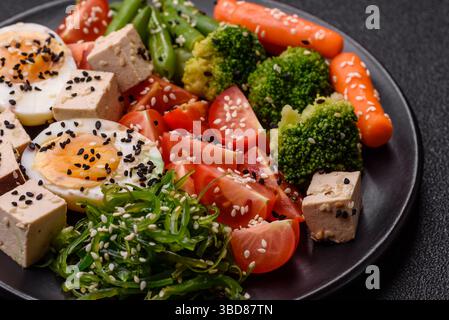 Veganer Salat, Schüsseln mit Kichererbsen, Brokkoli, Tomaten, Tofu-Käse und gekochten Eiern. Vegetarische Mahlzeit mit Gemüse, Samen und Körnern Stockfoto