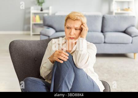 Ernste Und Traurige Seniorin Sitzt Zu Hause Im Stuhl Stockfoto
