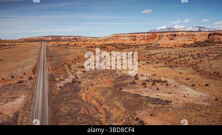 Luftstraße durch die Wüste in Richtung Klippen und verschneite Berge Stockfoto