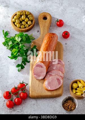 Wurst auf einem Brett mit Oliven und Kräutern Stockfoto