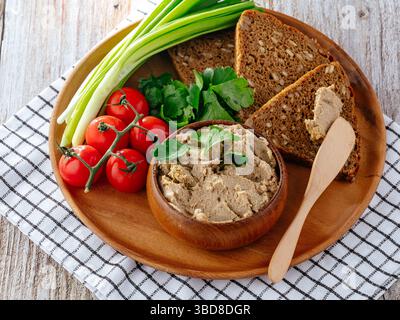 Brot mit Zwiebeln- und Tomatenpastete auf einem Holzteller Stockfoto