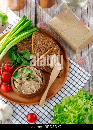 Brot mit Zwiebeln- und Tomatenpastete auf einem Holzteller Stockfoto