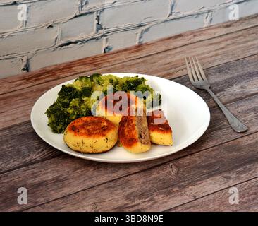 Kartoffelkoteletts gefüllt mit Hackfleisch und gekochtem Brokkoli auf einem Holztisch, eine Gabel in der Nähe. Nahaufnahme. Stockfoto