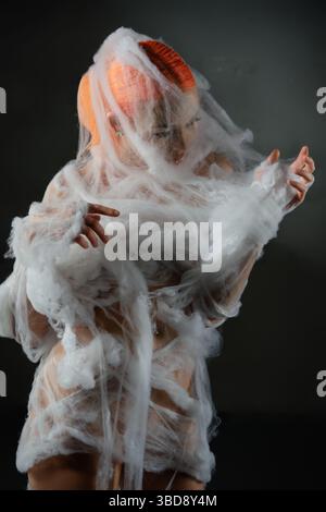 Frau verstrickt in einer fein gewebten roten Falle aus Netz und Schönheit Stockfoto