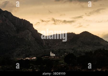 Goldene Stunde mit dramatischem Himmel und dem Dorf Beniarres inmitten der Berge, Spanien Stockfoto