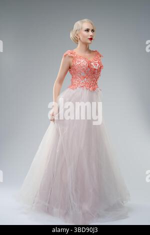 Die Frau posiert in einem blutgestreiften Brautkleid vor einem Atelierhintergrund Stockfoto