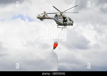 Maasmechelen, Belgien. Mai 2025. Die Abbildung zeigt einen Polizeihubschrauber, der am Freitag, den 23. Mai 2025, einen bambi-Eimer benutzt, um Wasser auf ein Feuer im Nationaal Park Hoge Kempen in AS zu kippen. Feuerwehren aus der Ost-Limburger Rettungszone wurden am Donnerstag, den 22. Mai 2025 Abend gegen 21.00 Uhr zu einem Waldbrand in der Mechelse Heide auf dem Gebiet von Maasmechelen und AS massenhaft ausgerufen. BELGA FOTO PINO MISURACA Credit: Belga Nachrichtenagentur/Alamy Live News Stockfoto