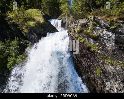 Mächtiger Waldwasserfall in Norwegen: Eine erfrischende Kaskade zwischen Felsen und hellem Grün in der malerischen Region Tromsø. Stockfoto