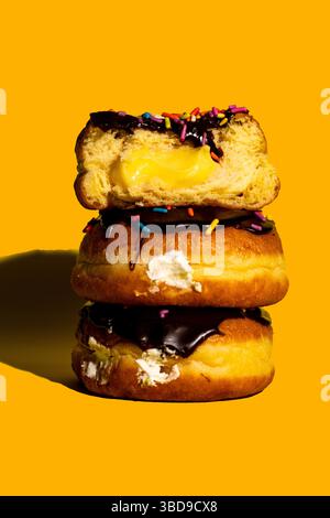 Drei Boston Cream Donuts auf gelbem Hintergrund Stockfoto