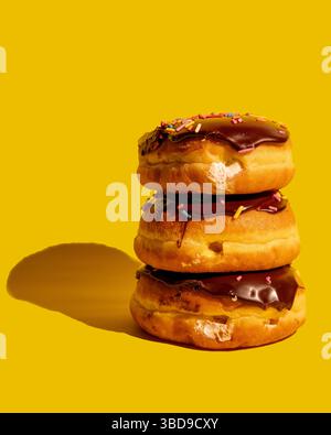 Drei Boston Cream Donuts auf gelbem Hintergrund Stockfoto