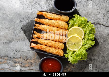 Tempura frittierte EBI-Garnelen mit gewürzten Saucen Nahaufnahme auf dem Teller auf dem Tisch. Horizontale Draufsicht von oben Stockfoto