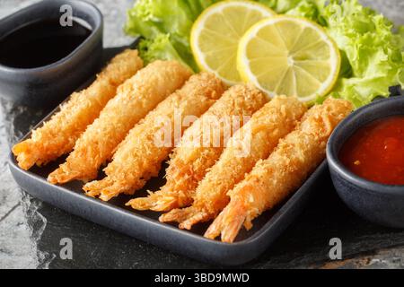 Köstliche Tempura-Garnelen serviert mit Zitrone und Salat und zwei Soßen aus nächster Nähe auf dem Tisch. Horizontal Stockfoto