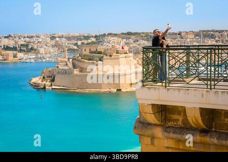 Valletta Malta Sommer, Blick auf ein junges Paar, das in den Upper Barrakka Gardens posiert und sich gegen den Grand Harbour in Valletta, Malta, fotografiert Stockfoto